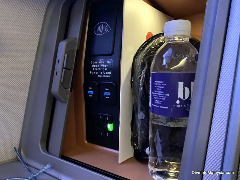 Little cupboard with water, power, headphones and menu in Singapore Airlines business class